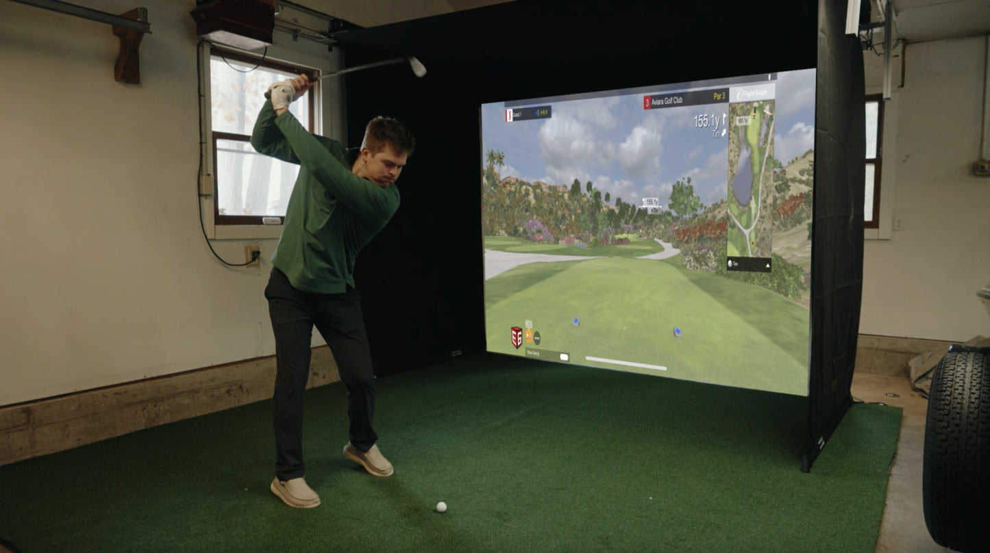 Golfer hitting balls into the Sports Screen Vanish retractable golf simulator enclosure