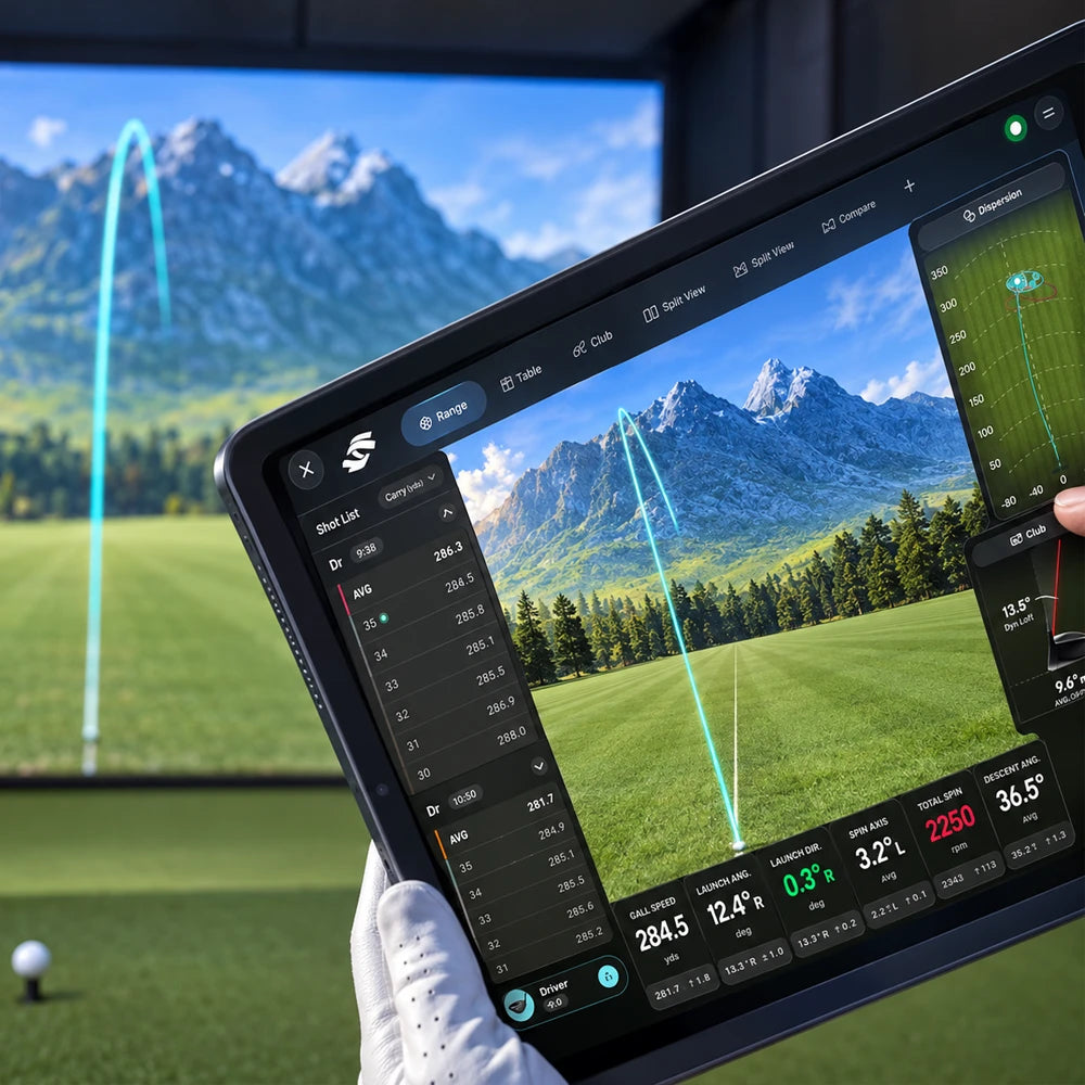 A person in a golf simulator holding a tablet displaying the Foresight Premier golf simulator app showing golf swing analysis overlay with flight path lines, scores, and driving range imagery of mountains and a green fairway.